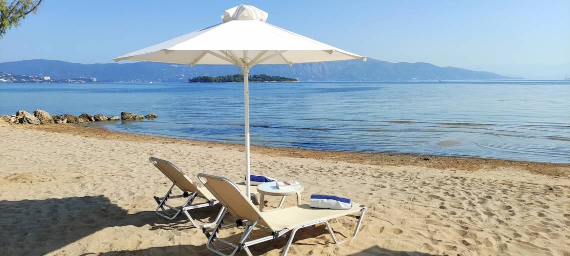 Strand mit zwei Liegen und einem Schirm im Schatten am Louis Kerkyra Blue Hotel