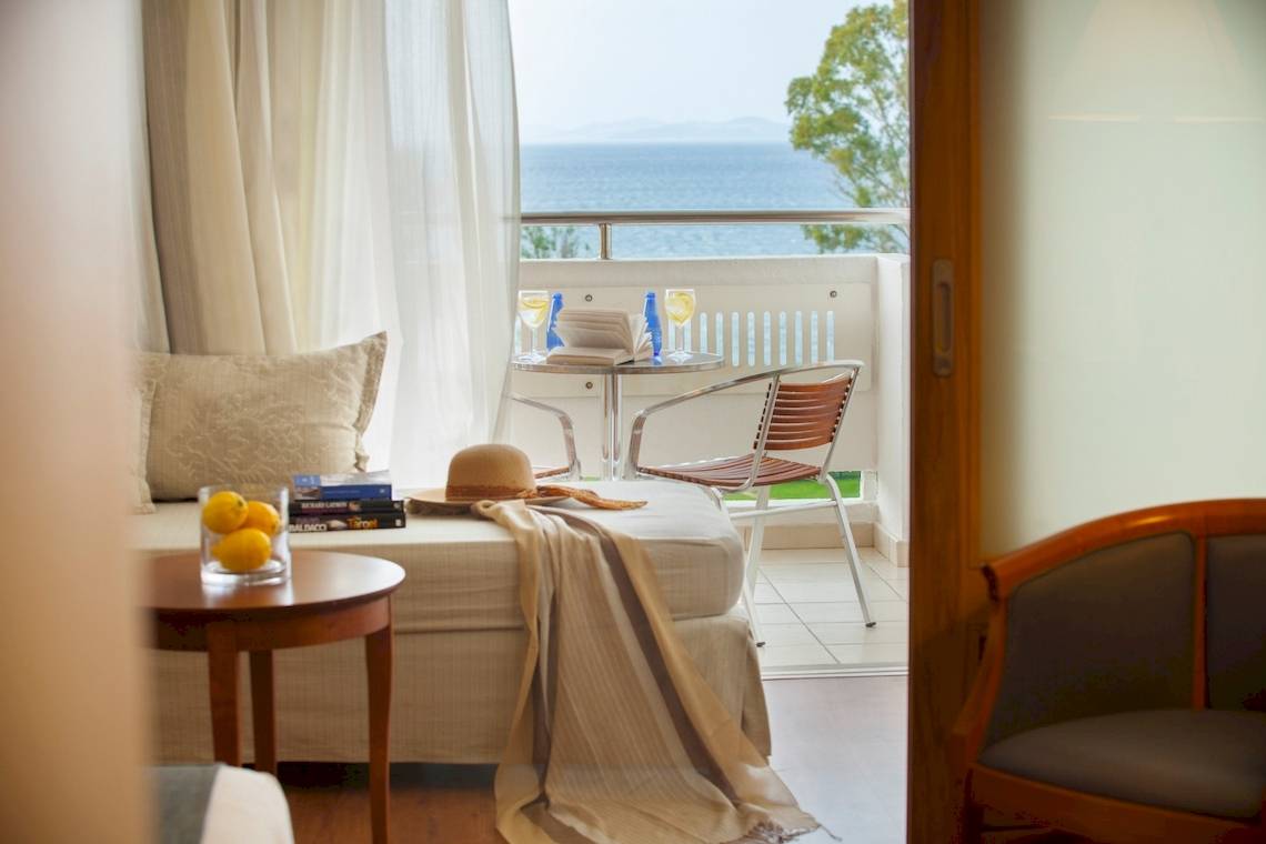 Hotelzimmer mit Meerblick im Louis Kerkyra Blue mit Balkon, Tisch, Stühlen, Büchern und Zitronen.