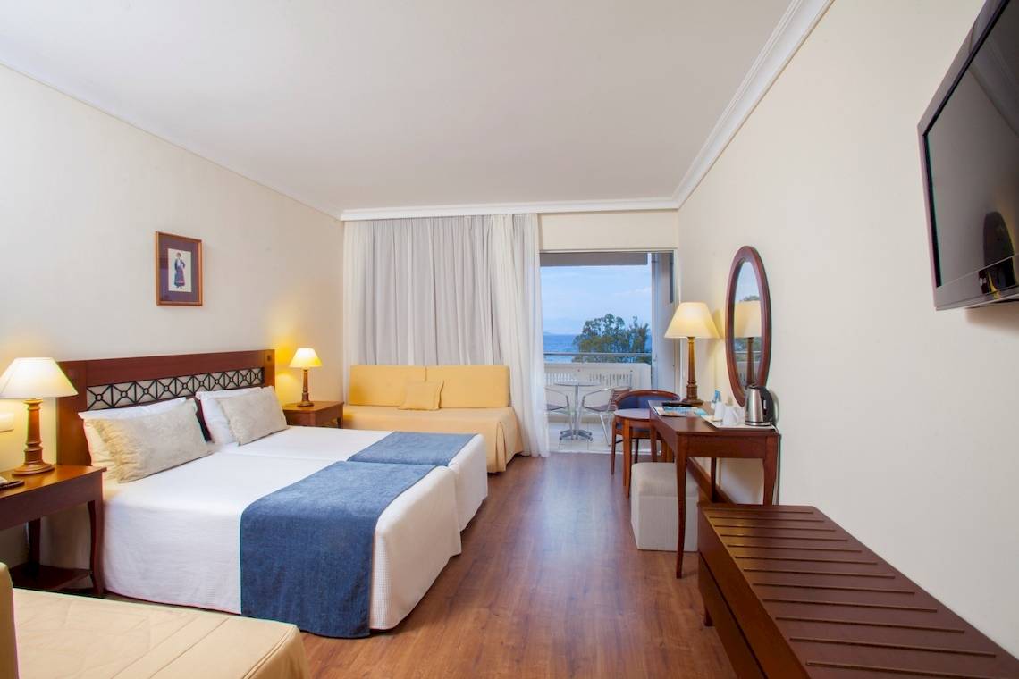 Doppelzimmer im Louis Kerkyra Blue Hotel mit Meerblick, zwei Betten, Sofa und Schreibtisch.