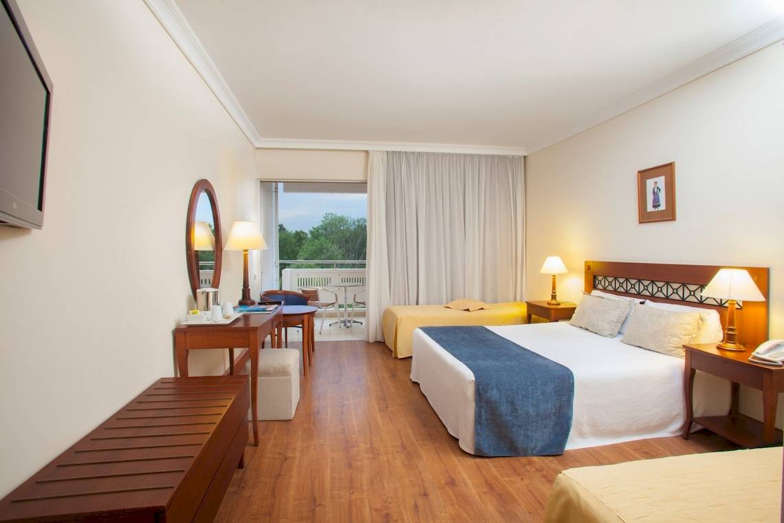 Innenansicht eines Hotelzimmers im Louis Kerkyra Blue mit zwei Betten, Schreibtisch und Balkon.