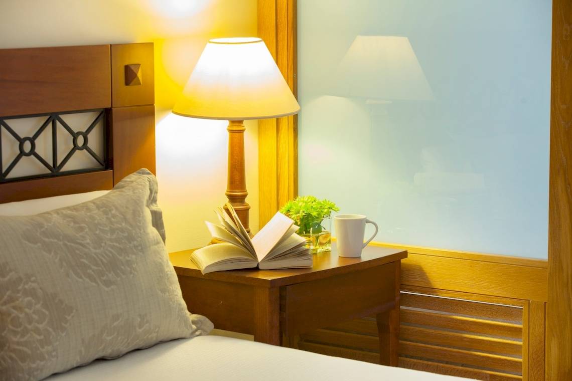 Bett mit Nachttisch, Lampe und Buch im Louis Kerkyra Blue Hotelzimmer