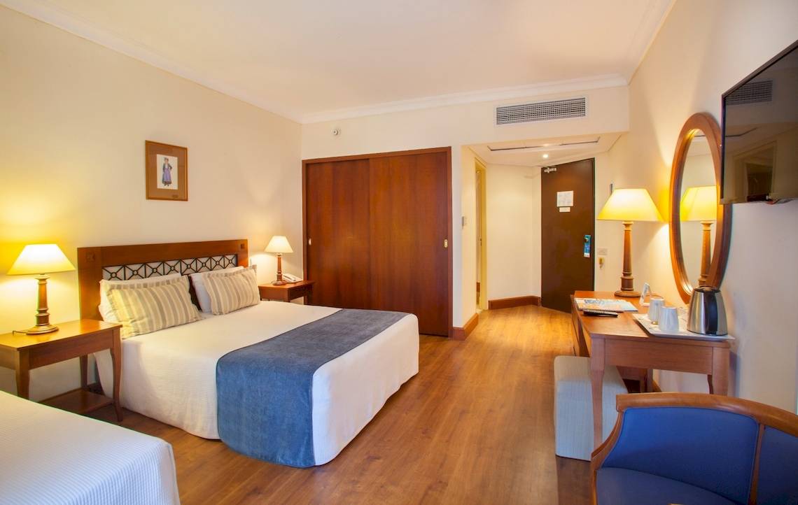Hotelzimmer des Louis Kerkyra Blue mit Doppelbett, Nachttischen und Schreibtisch.