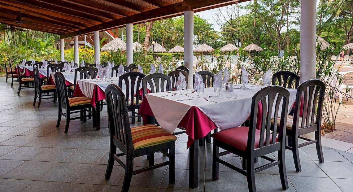 Restaurantbereich im Occidental Tamarindo Hotel mit Tisch und Stühlen, serviert für Mahlzeiten.