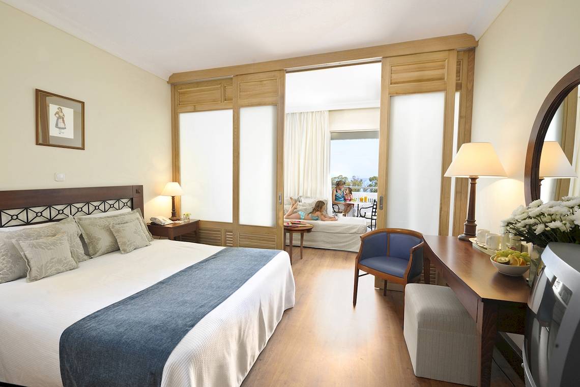 Doppelbett in einem Zimmer des Louis Kerkyra Blue Hotels mit Blick auf eine Terrasse