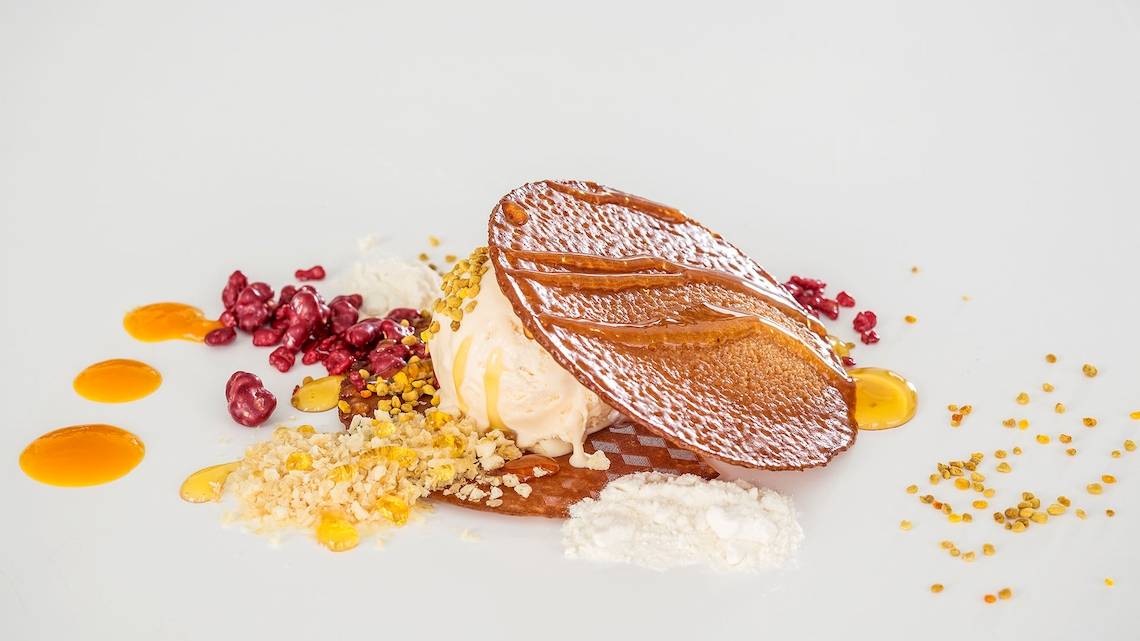Dessert von DeLight Boutique Hotel mit Eis, karamellisierten Blättern und Früchten auf weißem Teller