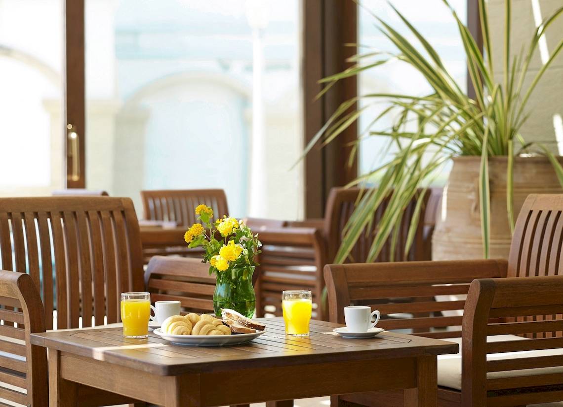 Frühstückstisch im Mitsis La Vita Beach Hotel mit Orangensaft, Croissants und Brot.