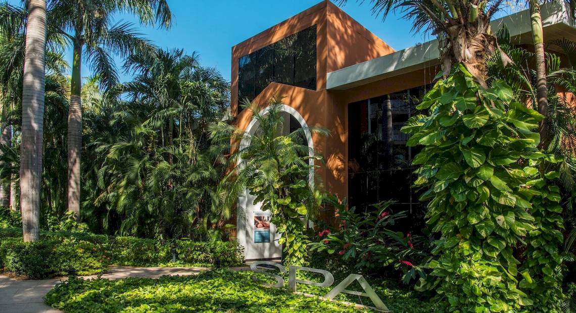 Spa-Eingang des Occidental Tamarindo Hotels, umgeben von Pflanzen und Palmen