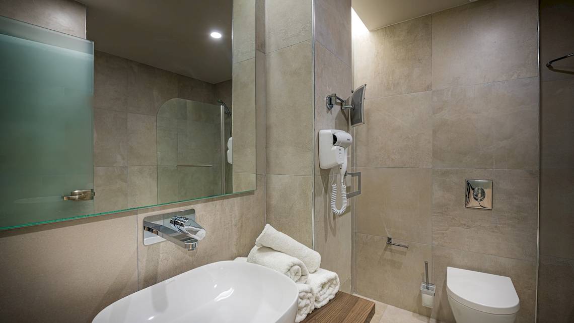 Badezimmer im Alexandra Beach Resort & Spa mit Waschbecken, Spiegel, Handtuchtrockner und Toilette.