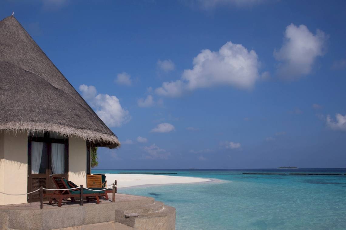 Coco Palm Dhuni Kolhu Hotel an einem weißen Sandstrand mit blauem Himmel