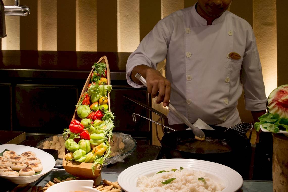 Koch mit Küchenutensilien und vorbereiteten Speisen im Coco Palm Dhuni Kolhu