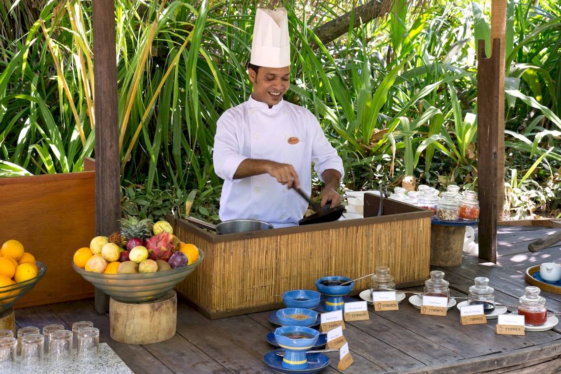 Koch bei Coco Palm Dhuni Kolhu bereitet Gericht zu, Früchte und Gewürze auf dem Tisch