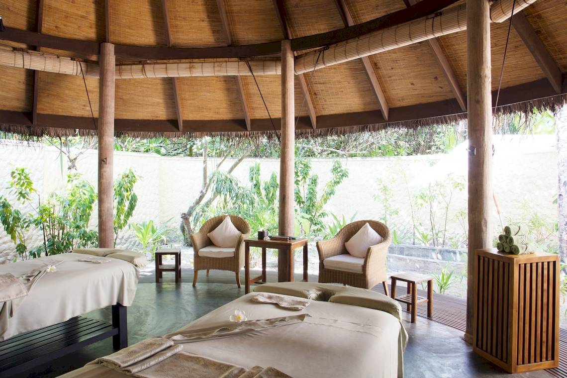Massageraum im Coco Palm Dhuni Kolhu Hotel mit zwei Liegen und Sitzmöbeln.
