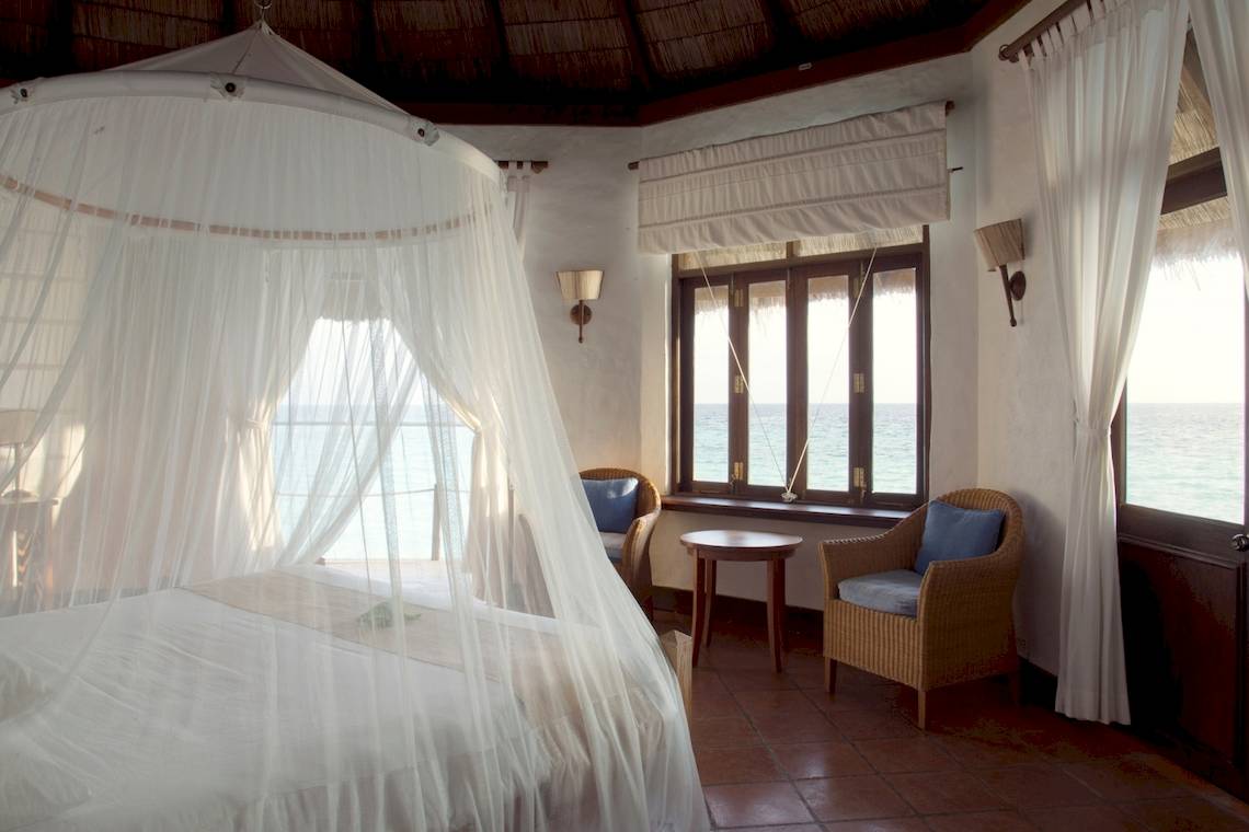 Bett mit Mosquito-Netz im Coco Palm Dhuni Kolhu Zimmer mit Meerblick.