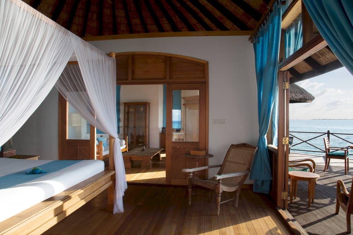 Coco Palm Dhuni Kolhu Hotel Zimmer mit Blick auf das Meer und eine Terrasse.