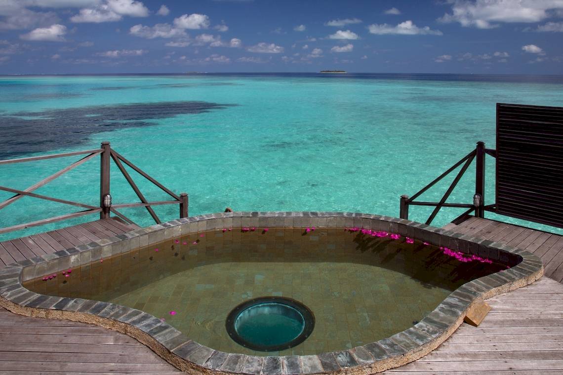 Aussicht auf den Pool des Coco Palm Dhuni Kolhu Hotels mit türkisfarbenem Wasser und blauem Himmel.