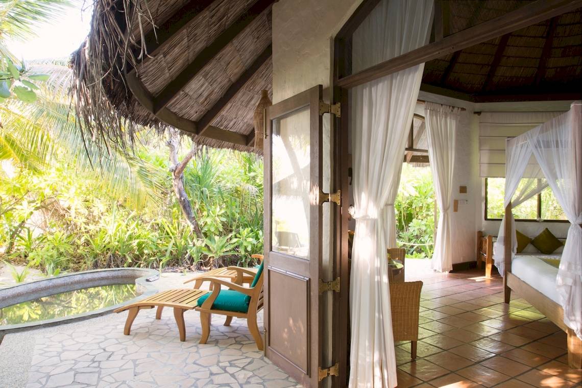 Zimmer im Coco Palm Dhuni Kolhu mit offenem Eingang und Pool auf der Terrasse.