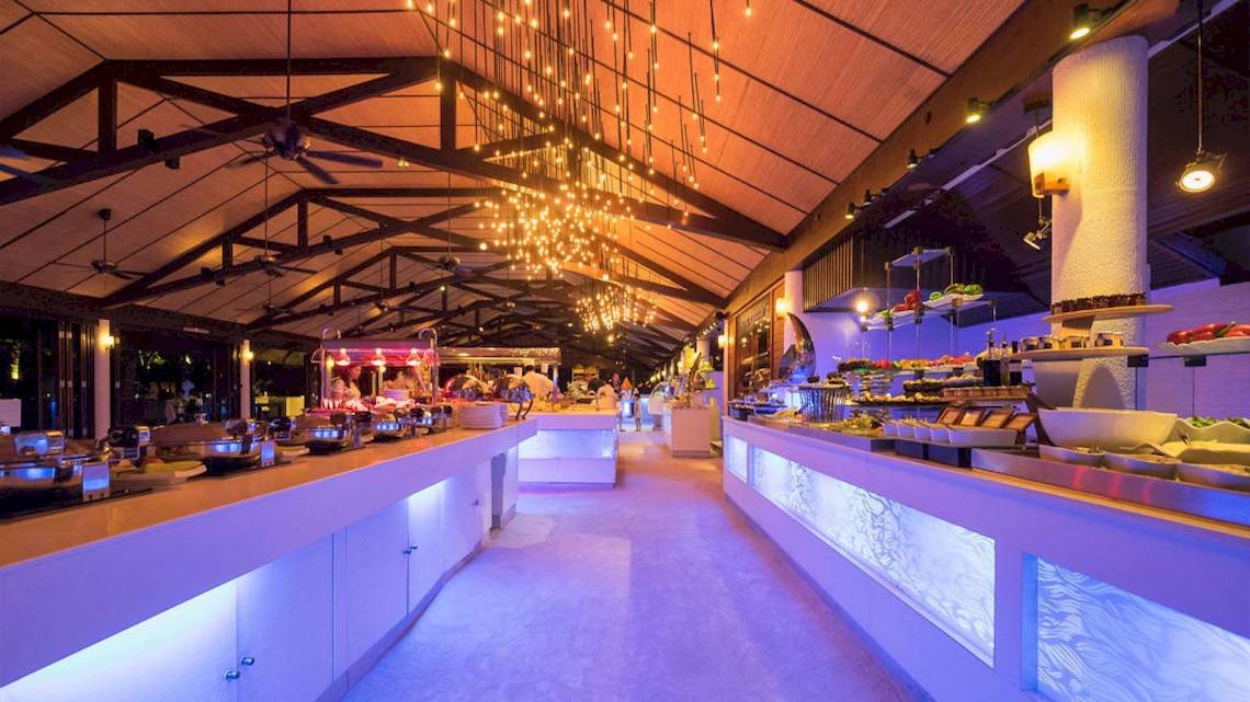 Buffetbereich im Lily Beach Resort & Spa mit gedeckten Tischen, Beleuchtung und Gästen.
