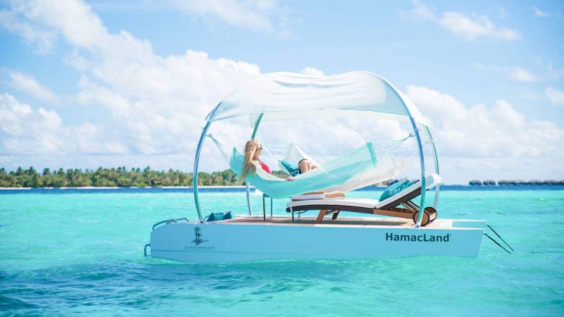 Zwei Frauen entspannen in einer Hängematte auf der HamaLand im Meer neben dem Lily Beach Resort & Spa.