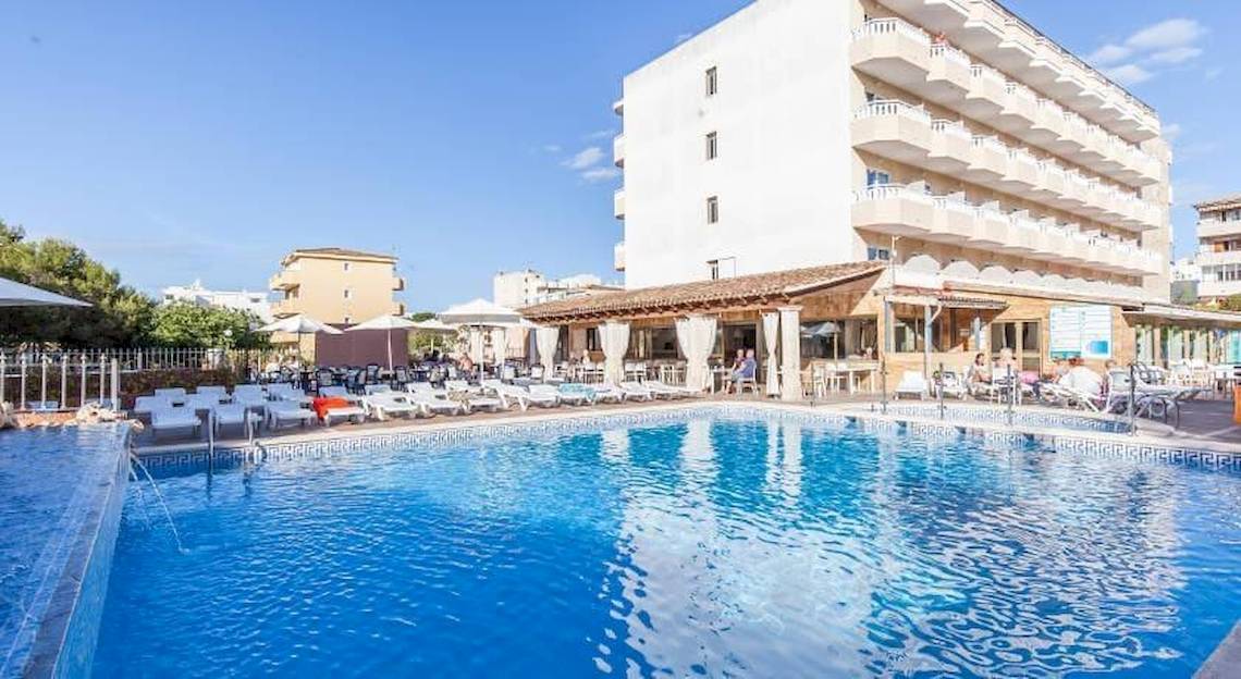 Außenpool des Bluesea Costa Bastian Hotels mit Loungeliegen und Gebäude im Hintergrund.