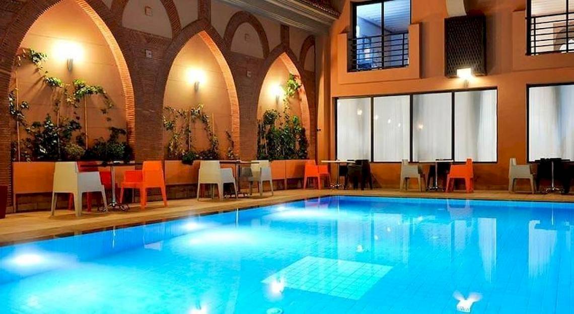 Poolbereich des Bluesea Costa Bastian Hotels mit blauem Wasser und bunten Stühlen.