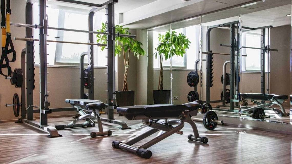 Fitnesscenter im AX The Victoria Hotel mit verschiedenen Trainingsgeräten und großen Fenstern.