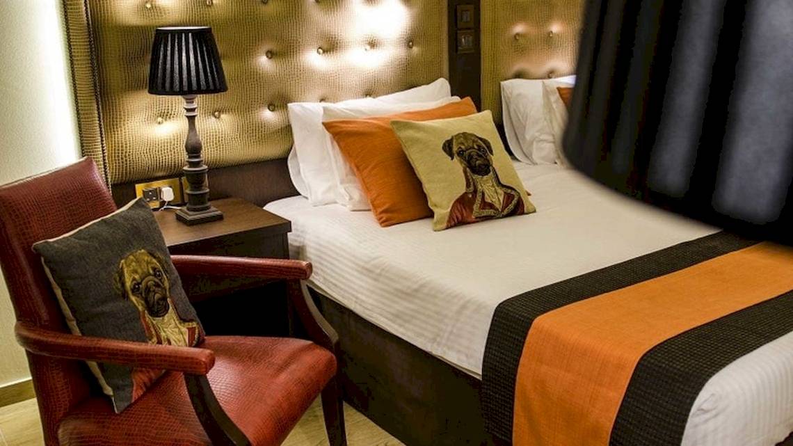 Hotelzimmer im AX The Victoria mit Bett, Kissen, Nachttisch und Stuhl.
