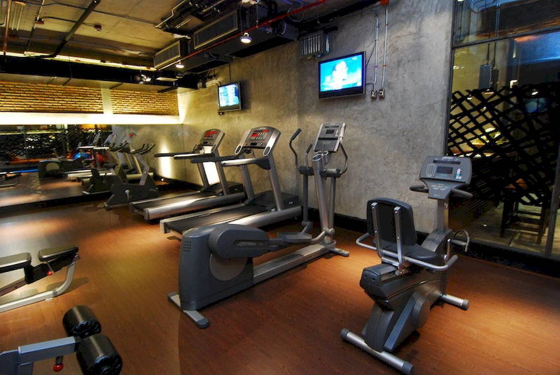 Fitnessstudio im Siam@Siam Design Hotel in Bangkok mit mehreren Laufbändern und Trainingsgeräten.