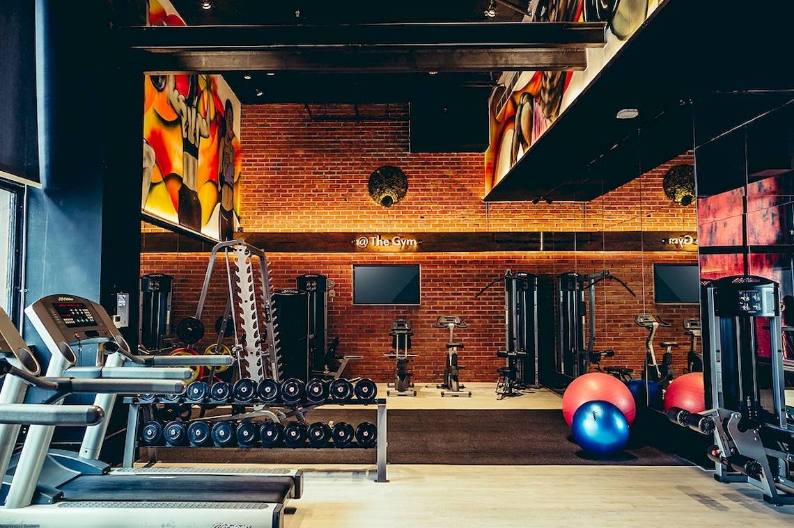 Fitness-Center im Siam@Siam Design Hotel Bangkok mit Laufbändern, Hanteln und Trainingsgeräten.