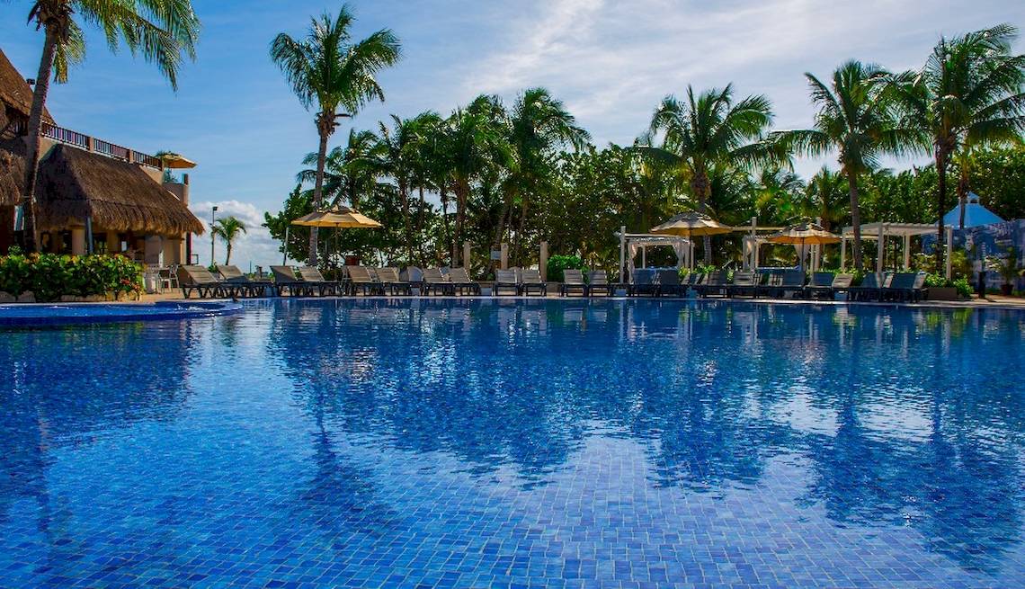 Außenpoolbereich des Catalonia Playa Maroma Hotels mit Liegestühlen und Sonnenschirmen