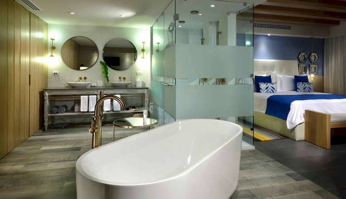 Badezimmer im Catalonia Playa Maroma Hotel mit Badewanne, Spiegelschrank und Doppelbett.