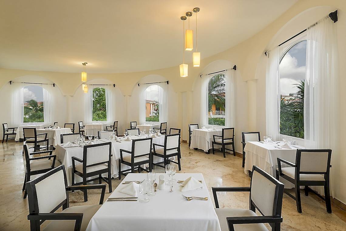 Innenansicht des Restaurants im Ocean Maya Royale Hotel mit gedeckten Tischen und Stühlen.