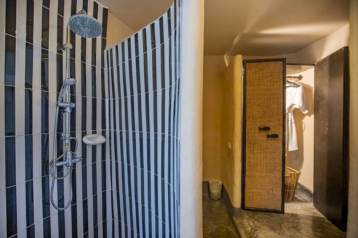 Dusche im Punnpreeda Beach Resort mit schwarzen und weißen Streifen und einer Kleiderstange.