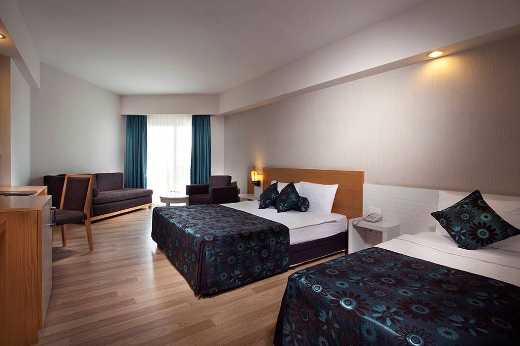 Doppelzimmer im Side Aluna Hotel mit zwei Betten, Sofa, Tisch und Fenstern.