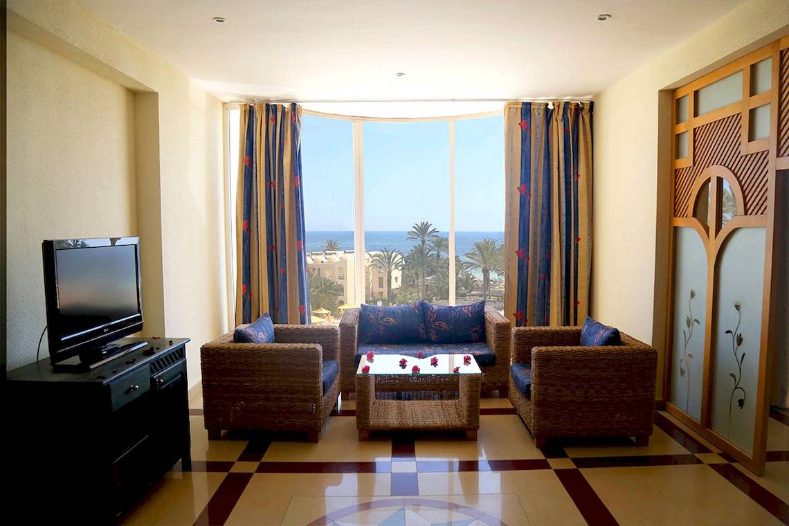 Wohnzimmer mit Meerblick im Eden Star Zarzis Hotel, mit Sofas, Tisch, Fernseher und großem Fenster.