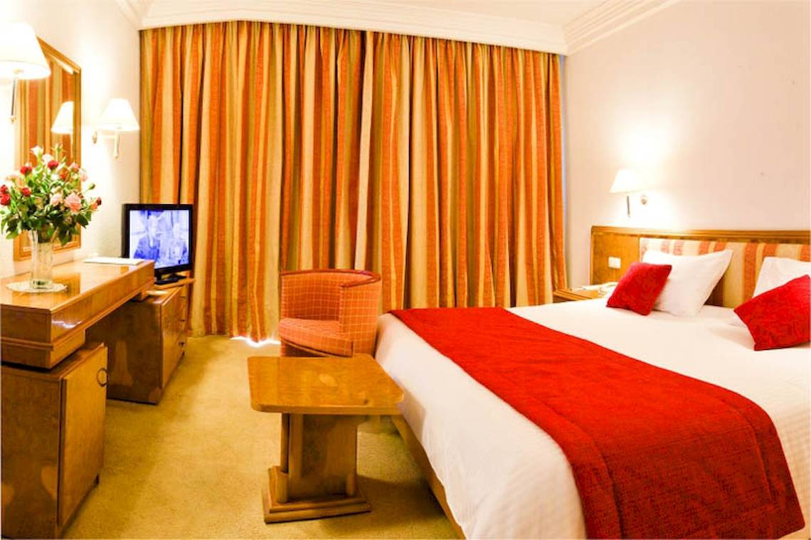 El Mouradi Palace Hotelzimmer mit Bett, Fernseher, Tisch und Stuhl.