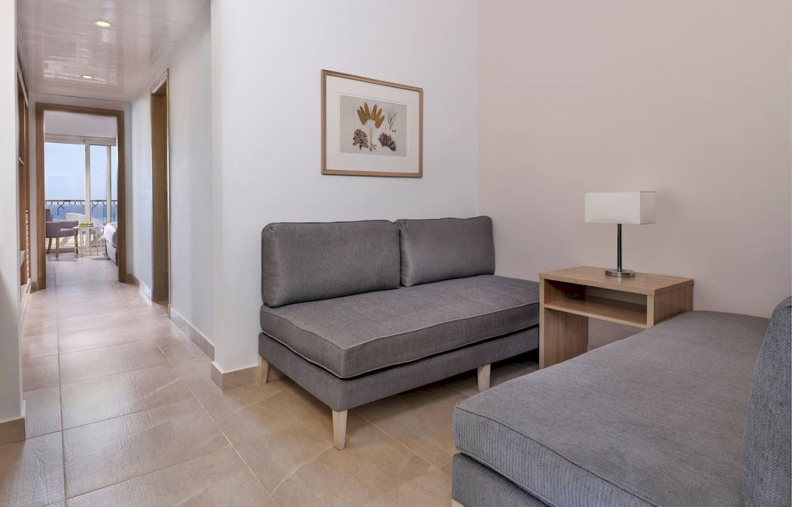 Hotelzimmer des Iberotel Costa Mares mit grauen Sofas und Nachttisch mit Lampe.