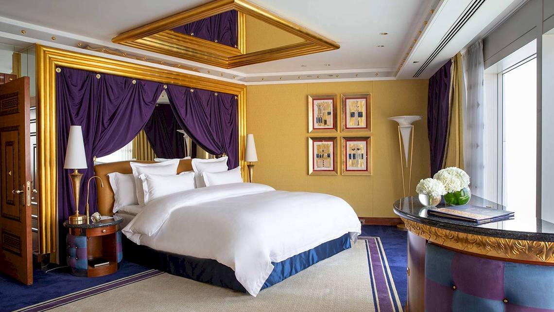 Schlafzimmer im Burj Al Arab Jumeirah Hotel mit goldenen Akzenten und violetten Vorhängen.