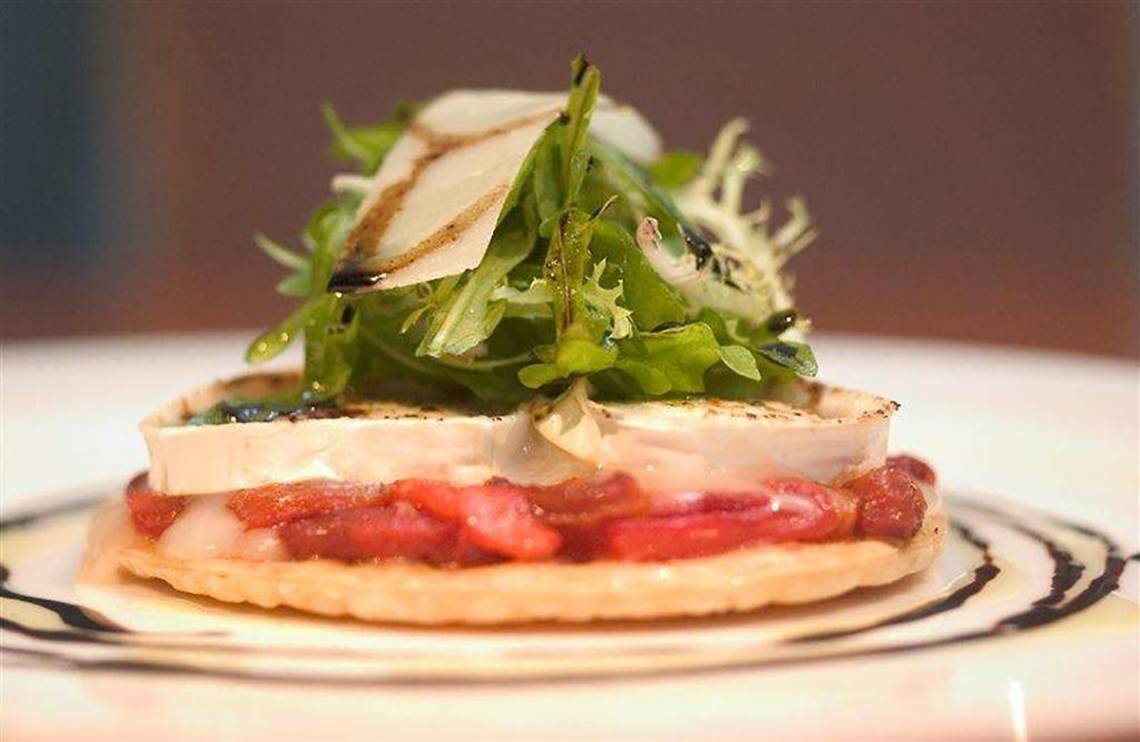 Nahaufnahme eines Tellergerichts mit einem Stück Käse, Tomaten und Salat.
