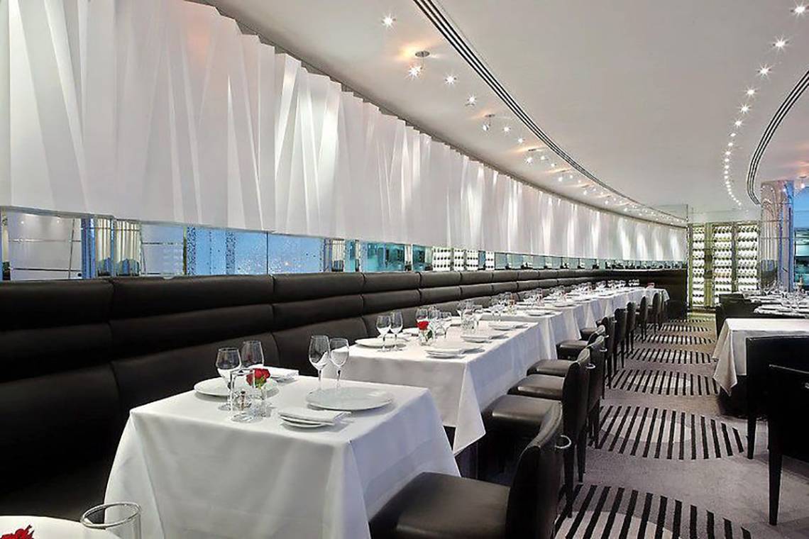 Innenansicht des Golden Sands Hotel Creek Restaurants mit gedeckten Tischen und geschwungenen Wänden.