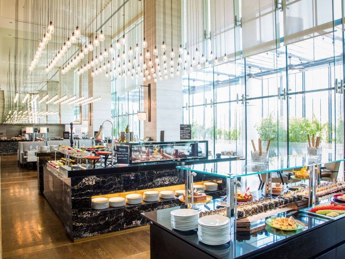 Restaurant im Pullman Dubai Downtown Hotel mit vielen Speisen und hängenden Lampen.