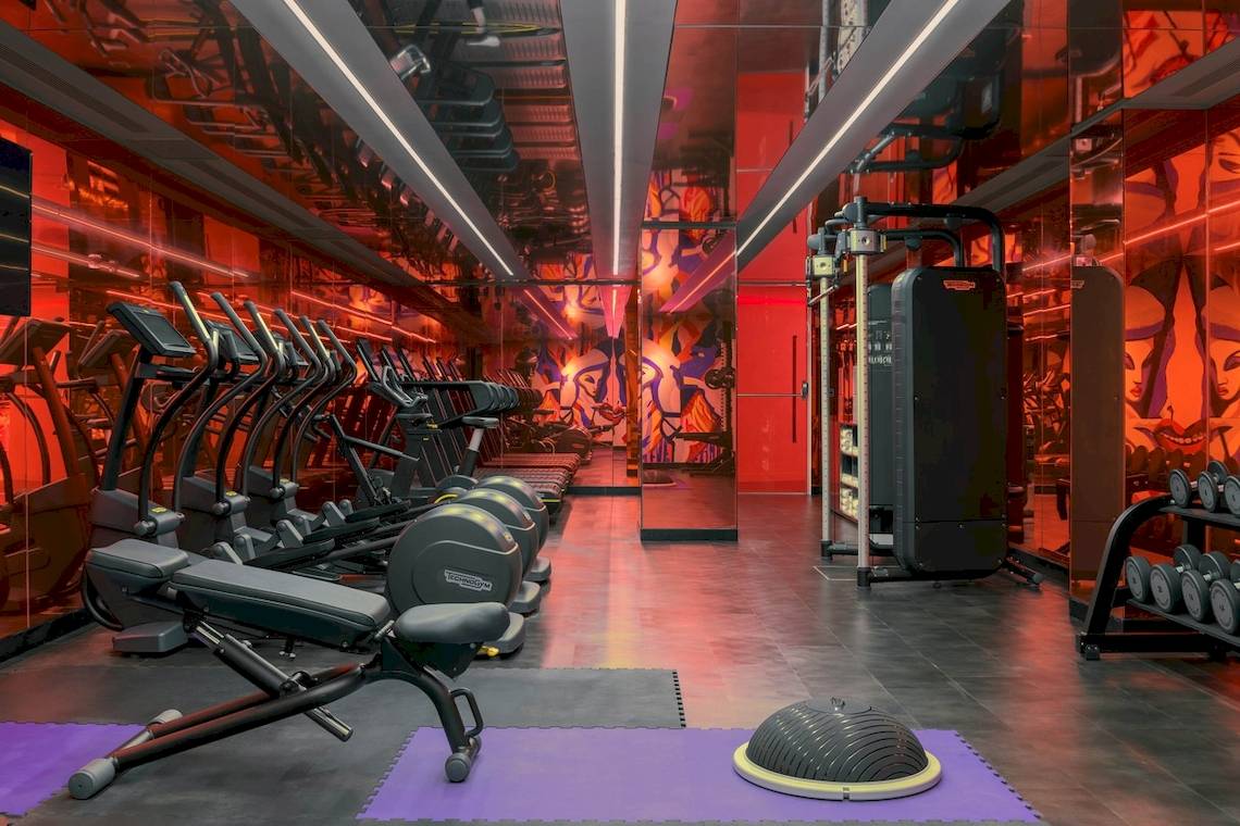 Fitnessraum im W Ibiza Hotel mit roten Wänden und moderner Ausstattung.