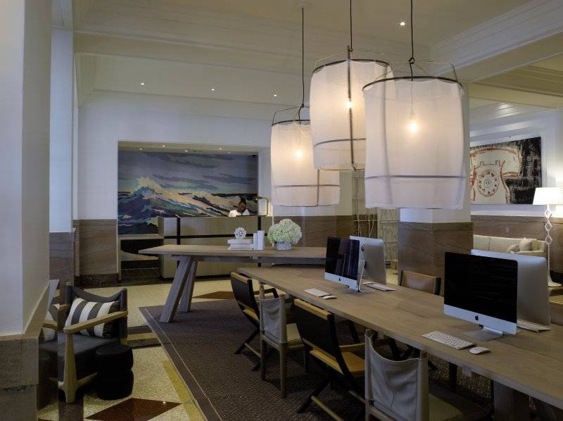 Arbeitsbereich im Victor South Beach Hotel mit Computern, Stühlen und Lampen.