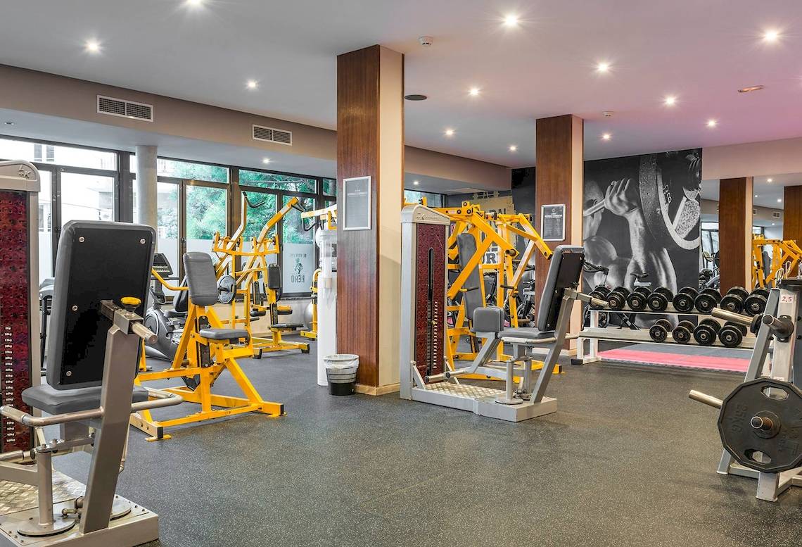 Fitnesscenter im Hotel Be Live Adults Only Marivent mit gelben Trainingsgeräten und Panoramafenstern.