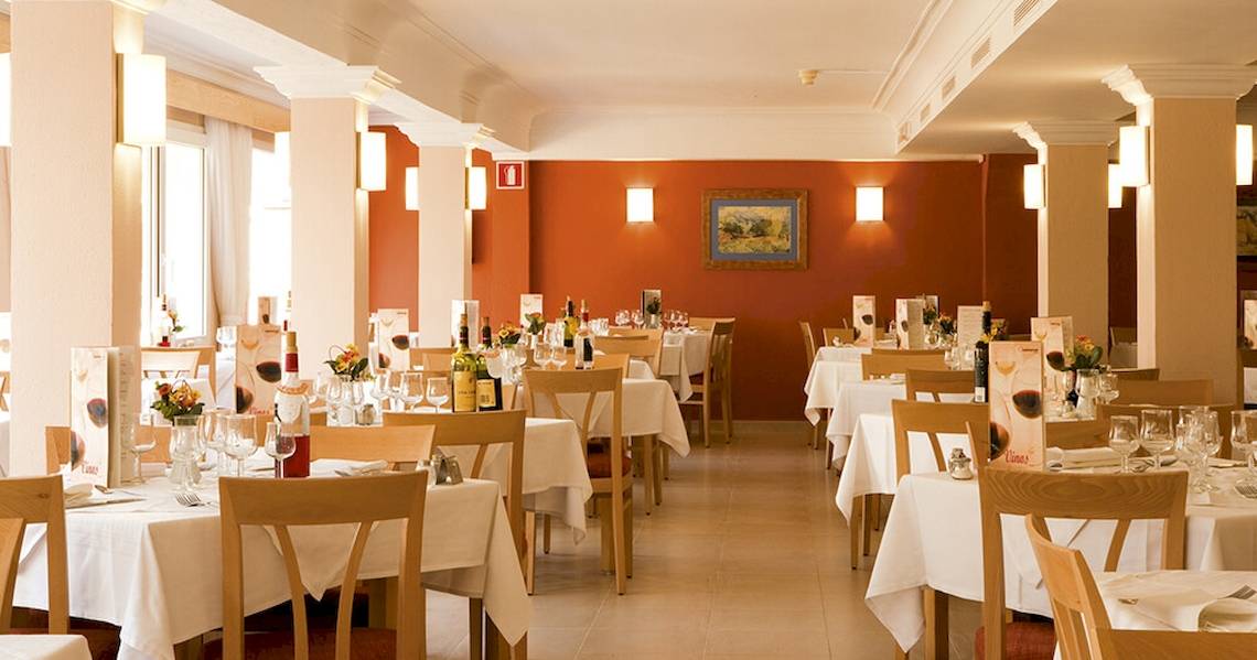 Innenansicht des Restaurants im Bikini Hotel mit geräumigen Tischen und Stühlen, dekorativ beleuchteten Wänden und kunstvollen Wandgemälden.