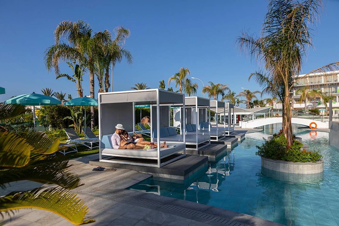 Außenbereich des Faros Hotel Ayia Napa mit Loungeliegen am Pool.