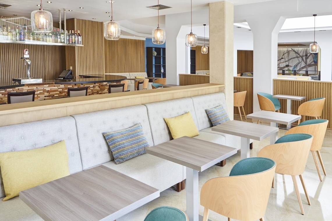 Innenbereich des Grand Leon & Spa Hotels mit Bar, Loungebereich und holzgetäfelter Wand.