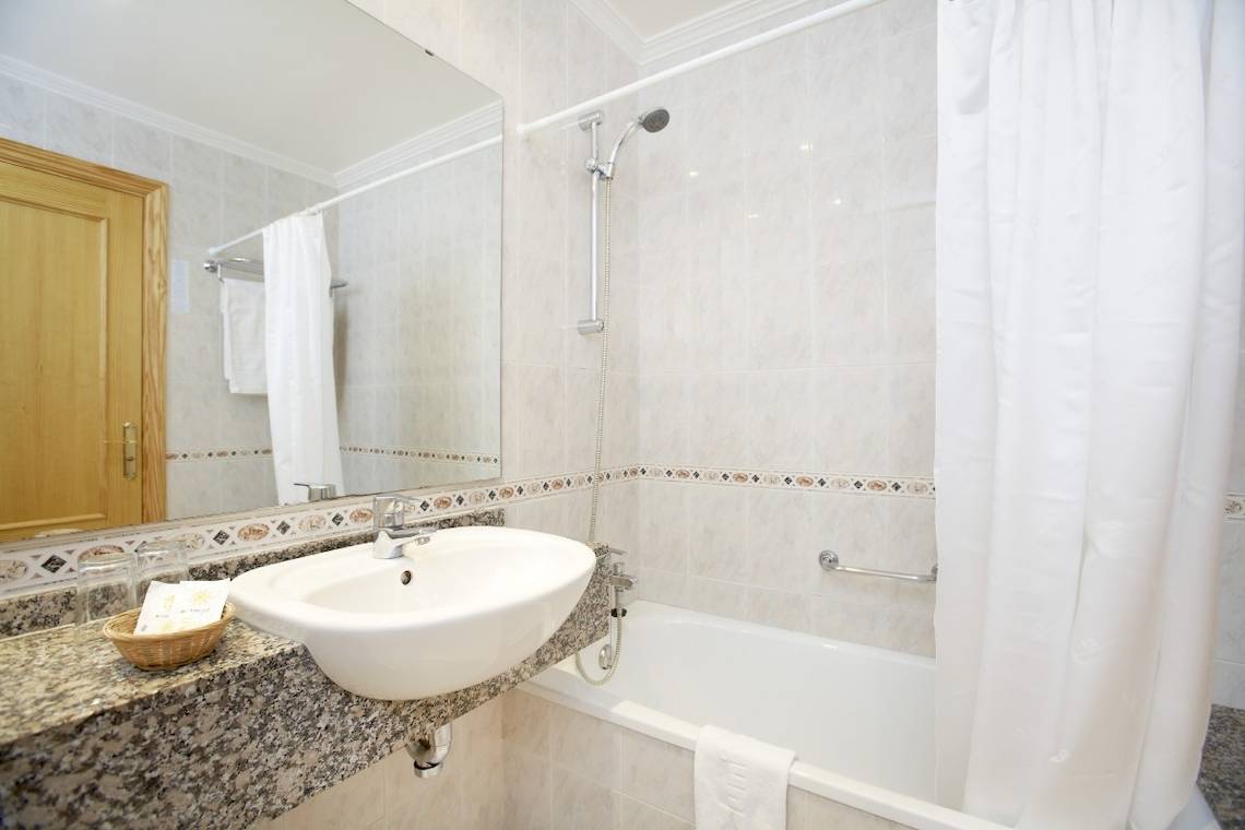 Badezimmer im Laguna Hotel mit Badewanne, Dusche und Waschbecken.