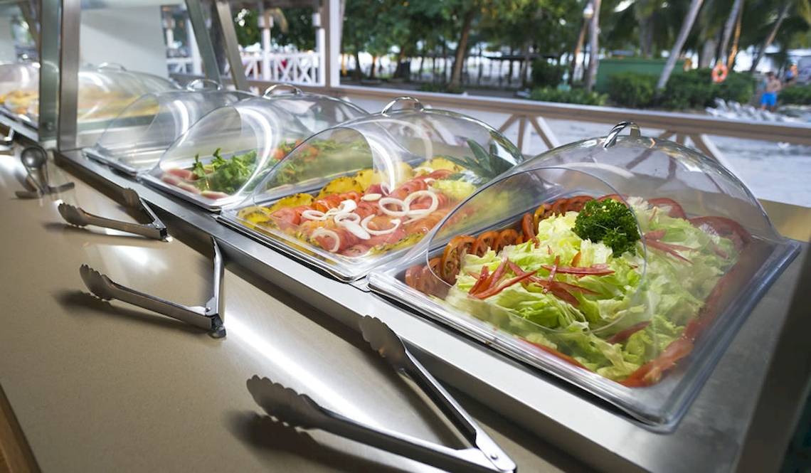 Buffet-Tisch im Coral Costa Caribe Beach Resort mit Salat, Tomaten und anderen Gemüsesorten.