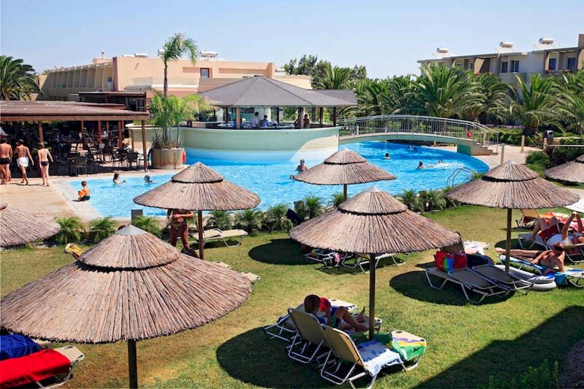 Außenbereich des Sandy Beach Hotel - Kos mit Swimmingpool, Liegestühlen und Sonnenschirmen.