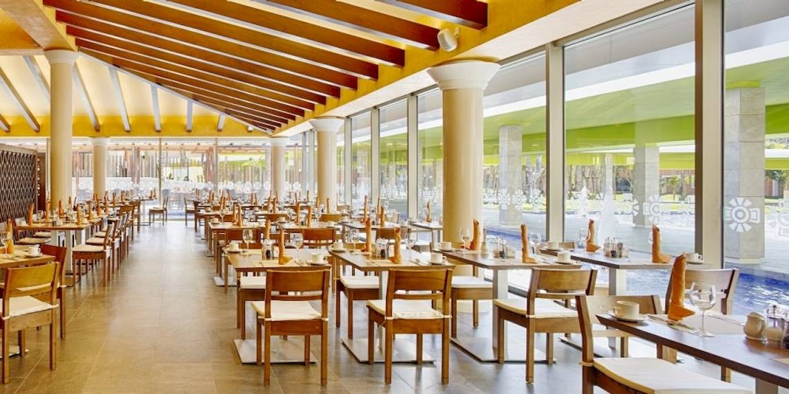 Innenansicht des Restaurants des Barcelo Maya Beach Hotels mit vielen Tischen und Stühlen.